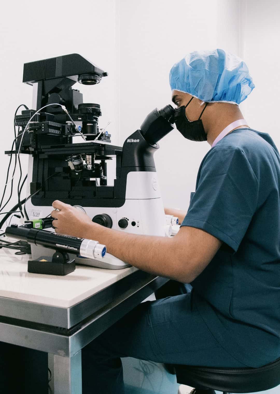 Embryologist performing genetic screening analysis under a laboratory microscope