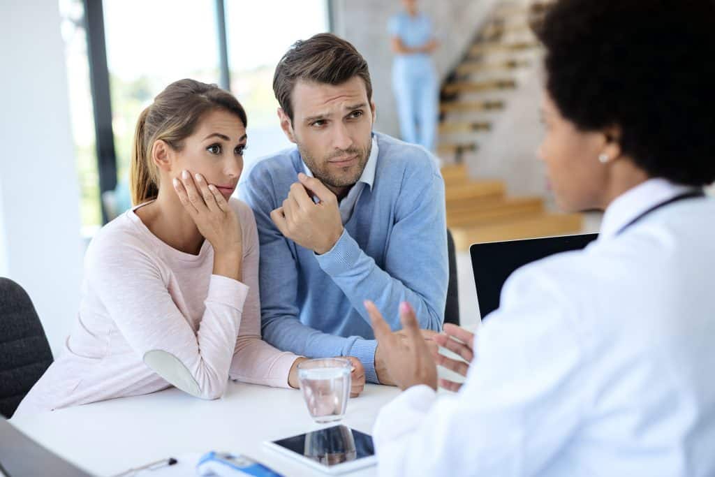 Worried couple listening to a doctor while having appointment at medical clinic.
